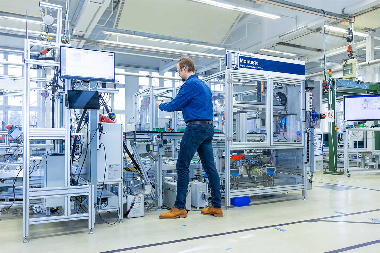 Ein Mitarbeiter der Professur Fabrikplanung und Intralogistik bedient einen Demonstrator in der Experimentier- und Digitalfabrik der TU Chemnitz.